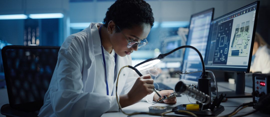 Modern Electronics Research, Development Facility: Black Female Engineer Does Computer Motherboard Soldering. Scientists Design PCB, Silicon Microchips, Semiconductors. Medium Close-up Shot